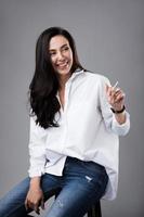 Beautiful middle aged fashion model wearing white shirt and jeans in a photo studio