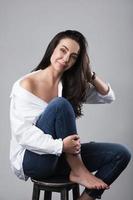 Beautiful middle aged fashion model wearing white shirt and jeans in a photo studio