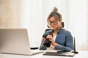 mujer feliz fotógrafa con una cámara sin espejo en el lugar de trabajo foto