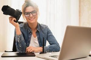 mujer feliz fotógrafa con una cámara sin espejo en el lugar de trabajo foto