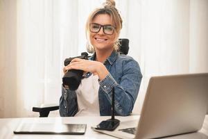 Happy woman photographer with a mirrorless camera at the workplace photo