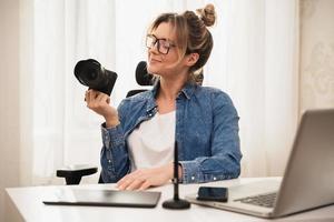 Happy woman photographer with a mirrorless camera at the workplace photo