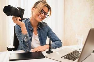 Happy woman photographer with a mirrorless camera at the workplace photo