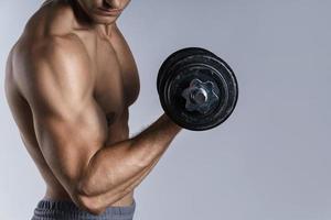 Young and muscular bodybuilder man working out with dumbbells photo