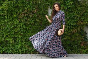 Gorgeous woman wearing beautiful maxi dress posing against wall with a wild grape photo