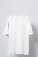 Blank white t-shirt hanging on a hanger against gray background photo