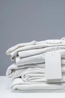 Stack of new white clothes with a blank garment tag photo