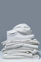 Stack of white clothes, trainers and baseball cap photo