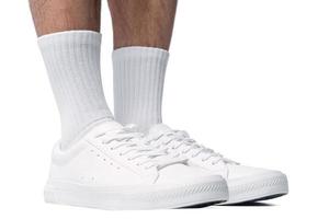 Closeup of male feet and shoes. Man wearing white trainers on white background. photo