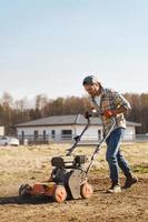 Man using aerator machine to scarification and aeration of lawn or meadow photo