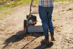 Man using aerator machine to scarification and aeration of lawn or meadow photo