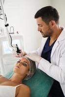 Doctor dermatologist and woman client during laser skin resurfacing treatment photo