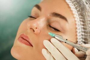 Woman getting injection of local anesthetic before mole removal treatment in a medical aesthetic clinic photo