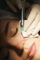 Woman getting injection of local anesthetic before mole removal treatment in a medical aesthetic clinic photo