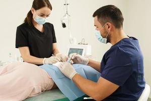 Doctor and nurse during dermatological surgery photo