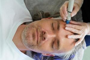 hombre de mediana edad durante una limpieza facial profunda en una clínica de cosmetología