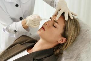 Doctor making marks on client's face before filler injection photo