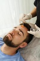 Young man during peeling treatment in beauty clinic photo