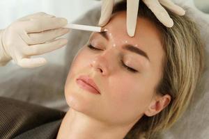 Doctor making marks on client's face before filler injection photo