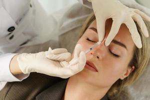 Woman during facial filler injections in aesthetic medical clinic photo