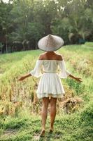 mujer con ropa natural y sombrero cónico asiático en el campo de arroz durante la puesta de sol foto