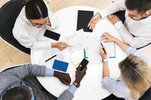 Multi-ethnic business people during meeting in modern office sitting at the round table photo