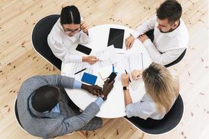 Multi-ethnic business people during meeting in modern office sitting at the round table photo