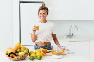 mujer alegre con un vaso grande de jugo de naranja fresco en casa foto