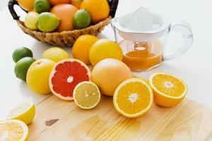 Juicer and various citrus fruits on white kitchen table photo