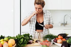 una mujer se corta accidentalmente el dedo mientras cocina en casa en una cocina blanca foto