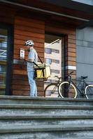 Express food delivery courier with insulated bag using intercom. photo