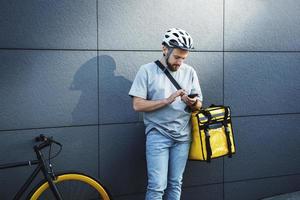 Express food delivery courier with insulated bag looking at phone. photo