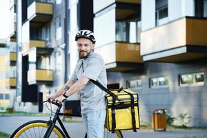 Express food delivery courier with insulated bag standing with bicycle. photo