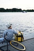 mensajero de entrega urgente sentado en el muelle mirando al río. foto