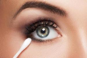 Female face with a cotton swab beside beautiful eye photo