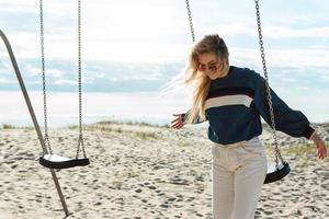 Young woman standing near swing at the beach. photo