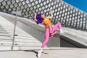 Carefree active woman dancer wearing colorful sportswear having fun on the street photo