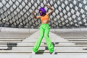 Active woman wearing colorful sportswear performing on the street during summer day photo