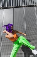 Carefree woman dancer wearing colorful sportswear having fun on the street during summer sunny day photo