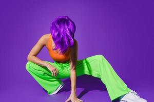 Carefree woman dancer wearing colorful sportswear having fun against purple background photo