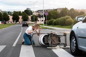 Horrified mother on the crosswalk after a car accident when a vehicle hits her baby pram. photo