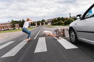 Shocked mother on the crosswalk after car accident when vehicle hits her baby pram photo