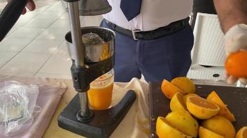 Ein Mann macht frisch gepressten Orangensaft aus natürlichen frischen Orangen mit einem manuellen Entsafter im Urlaub in einem touristischen warmen östlichen tropischen Land Southern Paradise Resort im Urlaub video