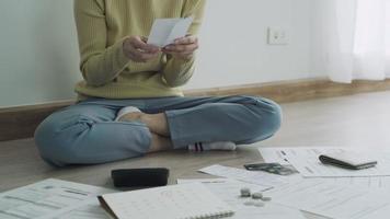 crédit de la dette et concept de problème financier. une femme asiatique est assise et revérifie les factures et le stress parce qu'elle ne gère pas la dette du mois. femme couvrant le visage avec les mains et se sentant stressée. video