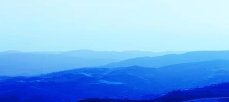 Layers of mountain ranges stacked in blue silhouette. Aerial perspective of blue hills. photo