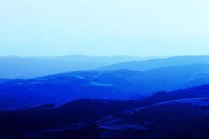 capas de cadenas montañosas apiladas en silueta azul. perspectiva aérea de colinas azules. foto