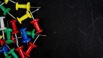 multicolored thumbtacks on a black background photo