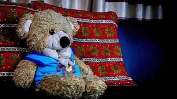 teddy bear in a blue t-shirt on a black sofa photo