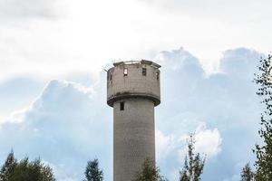 Exterior of abandoned water tower with collapsed roof and broken windows. photo