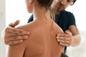 hombre masajista haciendo masaje de espalda para su cliente mujer foto